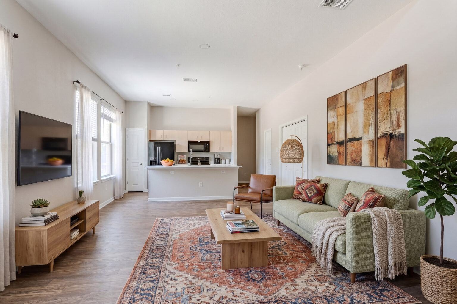 Virtually staged living room with green sofas and open kitchen island — Austin real estate listing photo
